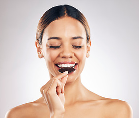 Image showing Woman, eating chocolate and thinking of diet for skincare, beauty and inner health on white background. Young person or model with cacao product, food or candy for skin care or dermatology in studio