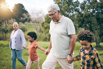 Image showing Park, grandparents and children holding hands while walking as a family together in retirement. Senior man, woman and grandkids in a nature garden for bonding on summer holiday or vacation with flare