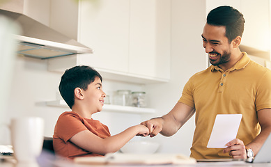 Image showing Fist bump, homework and father with child at their home in celebration of completed studying. Happy, smile and young dad bonding together with his boy kid in the kitchen of modern house or apartment.