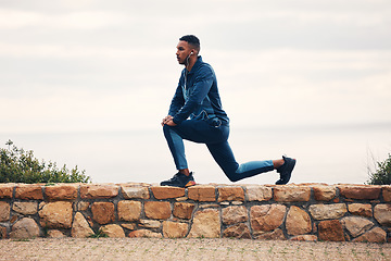 Image showing Man, lunge and stretching on rocks, outdoor earphones or for thinking, music for fitness, health or wellness. Runner guy, warm up and training for marathon with streaming, vision or workout in nature