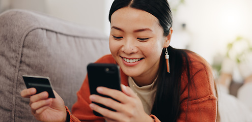 Image showing Asian woman, credit card and phone relaxing on her sofa online shopping, ecommerce and fintech easy payment. Young person in China typing bank information on cellphone for finance transaction at home