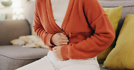 Image showing Stomach ache, cramps and hands of woman with abdomen pain due to constipation, menstruation or ibs issue. Sick, home and person suffering and holding belly in a house lounge, couch and living room