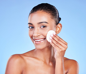 Image showing Woman, face portrait and cotton pad for skincare, cosmetics and aesthetic glow on blue background in studio. Happy young indian model, facial cleaning and beauty of dermatology, shine and wipe makeup