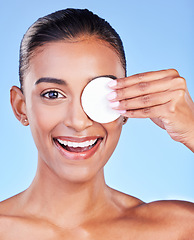 Image showing Portrait, woman and cotton pad on eyes for healthy skincare, cosmetics or smile on blue background in studio. Face of happy indian model, facial cleaning or beauty of dermatology, glow or wipe makeup