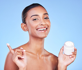 Image showing Cream jar, portrait and woman in studio with facial product for aesthetic skincare, dermatology or smile on blue background. Happy indian model, face lotion and glow of cosmetics container for beauty