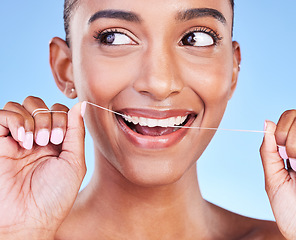 Image showing Woman, smile and floss teeth in studio for healthy dental care, gum gingivitis or plaque on blue background. Face, happy indian model and oral thread for cleaning mouth, fresh breath or tooth hygiene