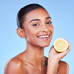 Image showing Lemon, portrait and woman in studio for beauty, vitamin c cosmetics and natural nutrition. Happy indian model, healthy skincare and citrus fruits for vegan dermatology, detox diet and blue background