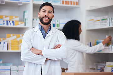 Image showing Medicine, pharmacy and portrait of healthcare man at shelf with pills, stock or medication. Pharmacist person or medical staff with arms crossed and smile at pharmaceutical, drugstore or retail shop