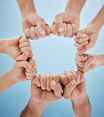 Image showing People, hands together and fist bump in teamwork, unity or community below blue sky background. Low angle, closeup or group goals in team building, motivation or support in trust on mockup space