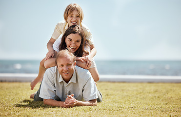 Image showing Portrait, mockup and family in a pile on grass by the ocean together for travel, vacation or holiday in a summer. Love, smile or happy with a dad, mom and son on the ground in a stack at the sea