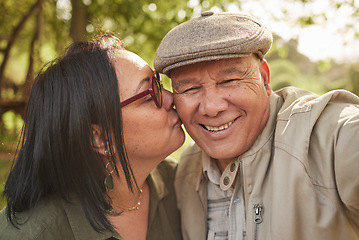 Image showing Selfie, kiss and senior couple in a park happy, bond and having fun in nature together. Portrait, love and elderly man with old woman in forest smile for profile picture, kissing and enjoy retirement