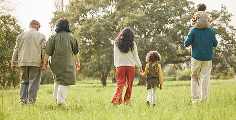 Image showing Love, holding hands and relax with big family in park for bonding, support and summer. Vacation, happy and holiday with people walking in grass field in nature for peace, generations or care together