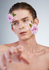 Image showing Touch, skincare and flowers on face of man in studio for beauty, natural cosmetics and creative. Glow, idea and floral art with model on white background for makeup, spa treatment and wellness