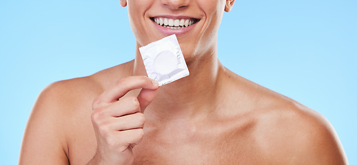 Image showing Smile, hand and man with a condom on a blue background for security or birth control in sex. Happy, health and person or guy showing protection or a product for sexual safety choice or contraception
