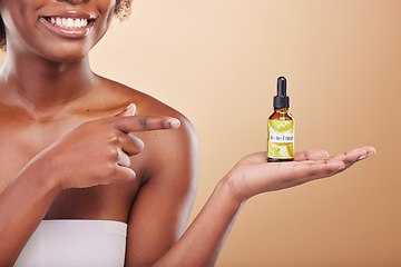 Image showing Hand, pointing and a woman with a product for skincare in her palm on a brown background in studio. Beauty, serum or treatment with a happy model showing a bottle for promotion or advertising