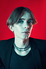 Image showing Fashion, portrait and gay man in makeup at studio isolated on a red background. Cosmetics, lgbtq style and face of model in cool clothes, punk aesthetic and serious person in Australia.