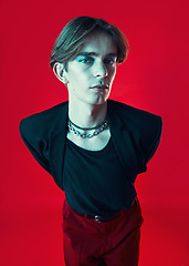 Image showing Fashion, lgbtq and portrait of a man in a studio with beauty face. stylish and classy outfit. Makeup, queer and young gay male model with funky, edgy and cool style isolated by a red background.