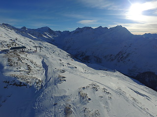 Image showing Morning, sunshine and mountains with snow in the winter for travel, climbing and hiking. Landscape, nature and the view of a natural environment with a blue sky in the Alps for adventure on rocks