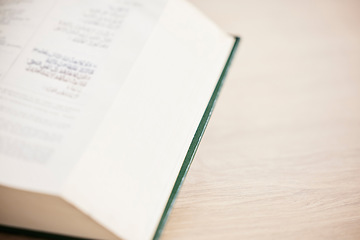 Image showing Islam, table and closeup of a Quran for reading, support and hope from a book in a house. Closeup, desk and an Arabic or Muslim teaching for prayer, spiritual faith or education from holy scripture