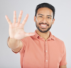 Image showing Smile, hand and portrait of man with stop gesture happy for communication isolated in a studio white background. Asian, sign language and confident young person with signal, symbol and hello sign