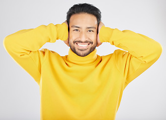 Image showing Portrait, smile and man cover ears in studio isolated on a white background. Face, noise and happy Asian person not listening, hearing loud sound and silence for peace, quiet and ignore to relax.