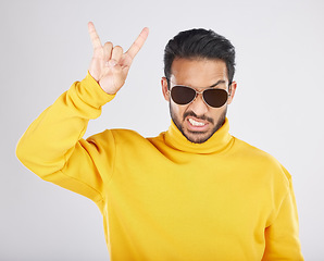 Image showing Man, sunglasses and horns sign in studio portrait, rock icon or hand gesture with clothes by white background. Young guy, model and devil fingers for attitude, fashion or crazy with emoji for culture