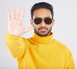 Image showing Man, palm and stop in sunglasses, studio portrait or emoji for opinion, rejection or no by white background. Indian guy, student or fashion model with hand, sign language and show gesture for review