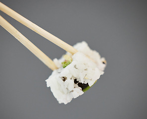 Image showing Seafood, sushi and chopsticks on studio background, California roll with seaweed for healthy Asian dining promo. Japanese food culture with rice, raw fish and avocado, restaurant menu offer or deal.