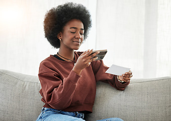 Image showing Paper, phone and black woman taking a picture on a sofa in the living room of her apartment. Technology. slip and young African female person with a cellphone for a photo in the lounge of her home.