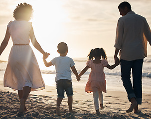 Image showing Sunset, beach and back of family holding hands in nature for travel, bond and fun together. Rear view, love and children with parents at the ocean for sunrise walk, relax and enjoy freedom in Mexico