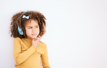 Image showing Thinking, problem and child with headphones on white background for planning, solution or music. Mockup, stress and a girl kid with a podcast, radio or audio idea with space for listening information