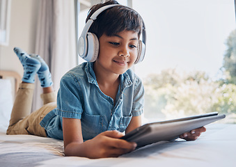 Image showing Boy, tablet and headphones on bed, reading of smile for streaming subscription, movie or relax with video. Male child, digital touchscreen and thinking in bedroom for audio, show or elearning in home