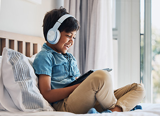 Image showing Happy, child and headphones with tablet on bed to watch funny movies, play video games or app. Boy kid laughing with digital technology for multimedia, listening to music or streaming cartoon at home