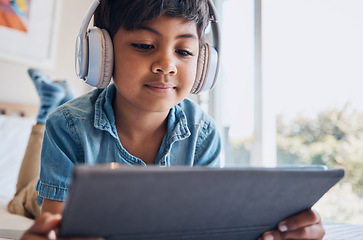 Image showing Boy kid, tablet and headphones on bed, reading or idea with e learninng, movie and relax with web video. Male child, digital touchscreen and thinking in bedroom for audio, show and streaming in home