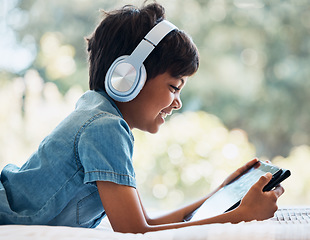 Image showing Boy, tablet and headphones on bed, smile and reading with idea, e learninng and movies on web to relax. Male kid, digital touchscreen and thinking in bedroom for games, music and streaming in home