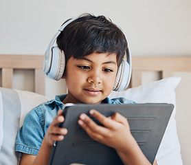 Image showing Face of boy, headphones and tablet in home for reading ebook, watch cartoon and play video games on elearning app. Child, kid and listening to multimedia, music and streaming movies on digital tech
