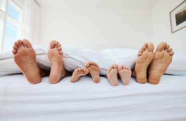 Image showing Feet, family and sleep in bedroom in home, relax in peace and rest in blanket in the morning together. Barefoot, bed and father, mother and children with parents in comfort, bonding and care in house