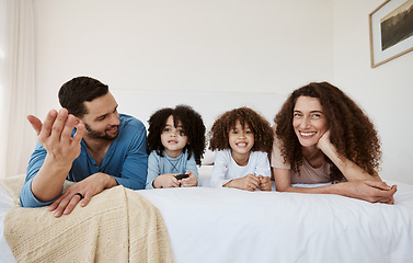 Image showing Parents, kids and watching tv on bed, together and relax with talking, choice or happy for movie in family home. Father, mother and children in bedroom for television, streaming subscription or video