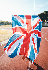 Image showing British flag, athlete running and race winner in celebration, sport achievement and training exercise on track. UK banner, victory and patriotism of person to support country in success of champion