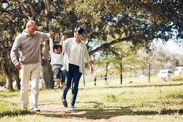 Image showing Happy, holding hands and grandparents with child in park for playing, love and support. Swing, smile and freedom with family walking on nature path for fun, summer vacation and happiness together