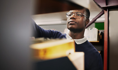 Image showing Knowledge, research and black man in a library search and learning on campus for studying and education in college. Smart, clever and young person in an academy with books on a shelf for an exam