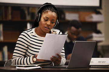 Image showing Woman, documents and headphones in library for research, studying and computer research or planning in university. African student reading paper, listening to music and laptop for focus and learning