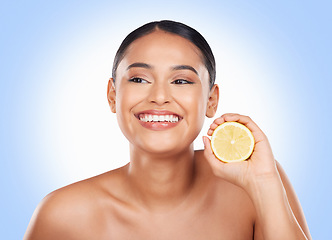 Image showing Beauty, lemon and happy studio woman with citrus fruit for organic skincare glow, facial detox or natural cosmetics. Happiness, spa and clean self care model with vitamin C product on blue background