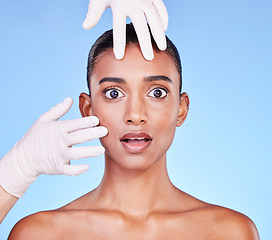 Image showing Scared, doctor and portrait of Indian woman for plastic surgery, cosmetics and skincare in studio. Dermatology, shock and hands on face of person for anti aging, botox and beauty on blue background