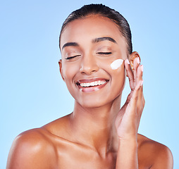 Image showing Skincare, cream and smile with woman and sunscreen in studio for beauty, facial or moisturizer. Spa treatment, cosmetics and collagen with face of person on blue background for makeup, glow or lotion