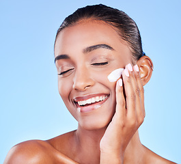 Image showing Skincare, cream and product with face of woman in studio for beauty, facial or moisturizer. Spa treatment, health and collagen with person and lotion on blue background for makeup, glow or sunscreen