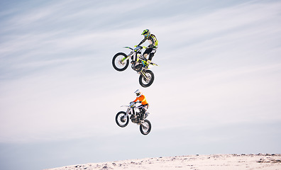 Image showing Sports, jump and people on motorcycle driving on sand, beach or training for a challenge, competition or desert rally. Dirt, motorbike and men in fearless extreme action, stunt or jumping in the air