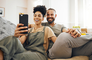 Image showing Interracial couple, selfie and smile on sofa, holding hands and together for memory, web blog or post on internet. Man, woman and happy for photography, profile picture and excited for social media