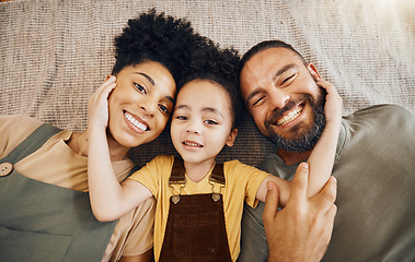 Image showing Portrait, family and a boy with his parents on the floor of the living room in their home together from above. Face, smile or love with an interracial mother, father and son lying down closeup