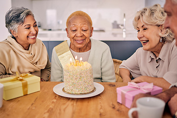 Image showing Senior women, birthday cake candle and party at a home with a present and gift with excited friends. Surprise, event dessert and retirement of elderly group at dining room table together with a smile